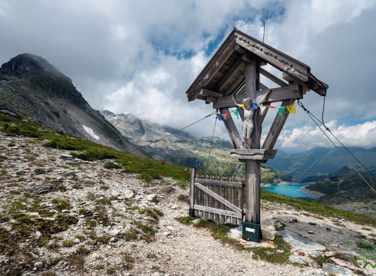 Weißsee Uttendorf Gletscherwelt Rudolfshütte Medelzkopf Kalser Tauern Direkt an der Rudolfshütte liegt der namensgebende Weißsee auf rund 2.250 bis 2.300 Metern Höhe. Was heute ein imposanter, türkis schimmernder Speichersee ist, war ursprünglich ein ganz natürlicher Bergsee. In den Jahren 1950 bis 1952 wurde der See im Zuge des Ausbaus der Kraftwerksgruppe Stubachtal durch den Bau einer 39 Meter hohen Staumauer drastisch verändert und zu einem Jahresspeicher umfunktioniert. Betrieben wird das Ganze von der ÖBB-Infrastruktur, um saubere Energie für den Bahnverkehr zu gewinnen. Gespeist wird der alpine Stausee vor allem durch das Schmelzwasser der umliegenden Gletscher, insbesondere des Sonnblickkeeses. Diese massive Umgestaltung hatte damals übrigens dramatische Folgen für die ursprüngliche Rudolfshütte: Die historische Schutzhütte aus dem Jahr 1873 musste weichen und wurde vor der Flutung gesprengt – ihre Trümmer versanken im aufgestauten See, ehe später an neuer Stelle das heutige Berghotel entstand.